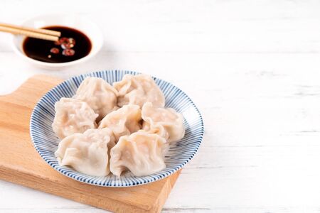 Fresh, delicious boiled pork, shrimp gyoza dumplings on white background with soy sauce and chopsticks, close up, lifestyle. Homemade design concept.の写真素材