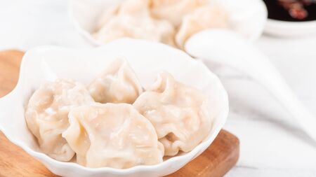 Fresh, delicious boiled pork, shrimp gyoza dumplings on white background with soy sauce and chopsticks, close up, lifestyle. Homemade design concept.の写真素材