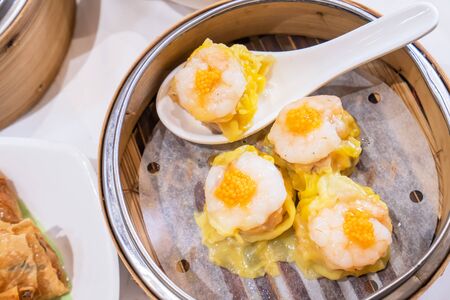 Siu Mai, one of Dim Sum yum cha, pork and shrimp steamed dumplings on restaurant house white background table for breakfast, lifestyle, close up.の写真素材