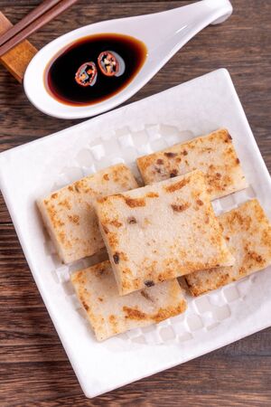 Delicious turnip cake, Chinese traditional radish cake in restaurant with soy sauce for new year's dishes, close up, copy space, top view, flat lay.の写真素材