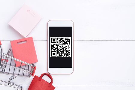 Abstract online shopping, mobile payment with QR code design concept element, colorful cart, paper bag on wooden table background, top view, flat layの写真素材