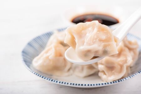 Fresh, delicious boiled pork, shrimp gyoza dumplings on white background with soy sauce and chopsticks, close up, lifestyle. Homemade design concept.の写真素材
