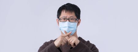 Portrait of young Asian man, saying no to coronavirus infection with wearing medical surgical blue...