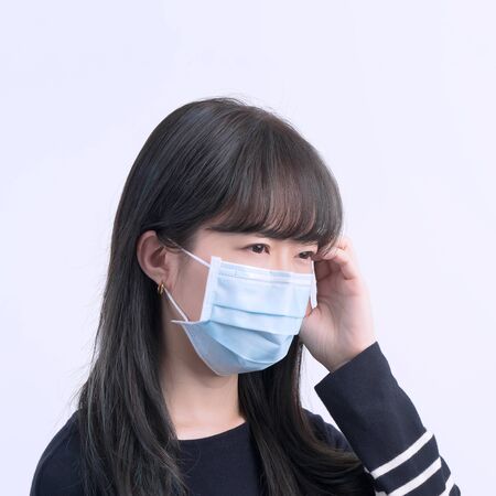 Young woman is feeling dizzy, headache, sick, unwell with wearing a medical blue face mask over the...