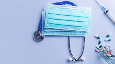 Mask with pills, stethoscope, syringe medical supply objects isolated on blue background, top view,...