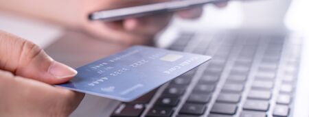 Online paying shopping, electronic payment with credit card, smart phone concept, laptop over white table background with shop cart trolley, close up.の写真素材