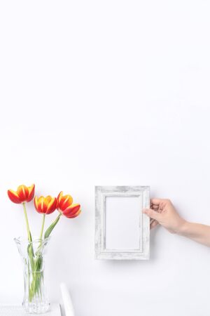 Tulip flower in glass vase with picture frame place on white wooden table background against clean wall at home, close up, Mother's Day decor concept.の写真素材