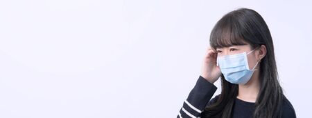 Young woman is feeling dizzy, headache, sick, unwell with wearing a medical blue face mask over the gray background, close up, copy space.の写真素材