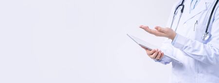 Doctor with stethoscope in white coat holding tablet, showing medical information, diagnosis, isolated on white background, close up, cropped view.の写真素材