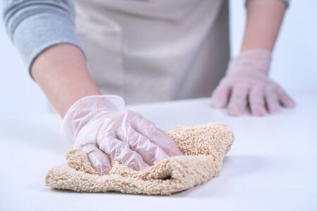 Young woman housewife is cleaning, wiping down home table surface to stop the spread of infection...