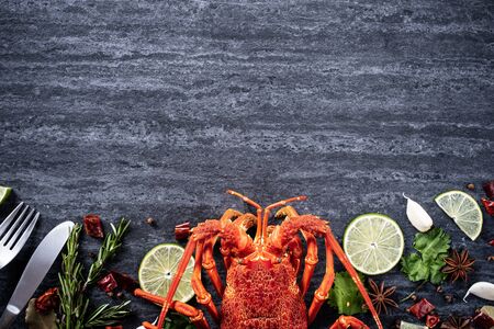 Cooked boiled lobster, delicious dinner seafood meal set with knife and fork on black stone slate background, restaurant menu design, top view, overheadの写真素材