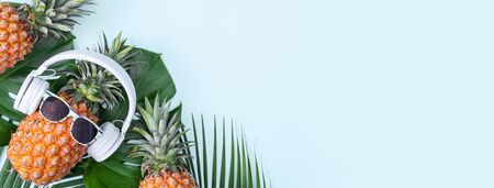 Funny pineapple wearing white headphone, concept of listening music, isolated on blue background...