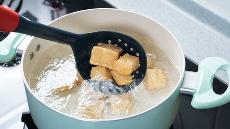 Cooking diced cubed dried tofu on gas stove in home kitchen, lifestyle, closeup.の写真素材