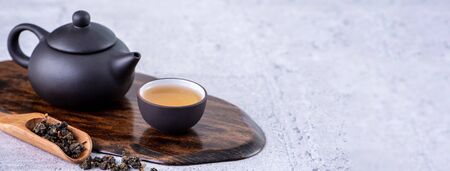 Hot tea in black teapot and cups and dry tea leaves over bright gray cement background, close up, copy space design concept.の写真素材