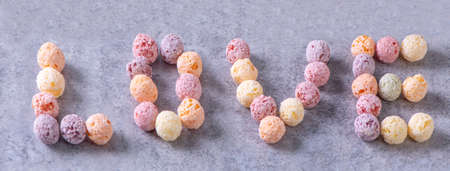 Colorful cereal corn balls mix, fruit flavor bowl sweets on gray cement background, close up, fresh,...