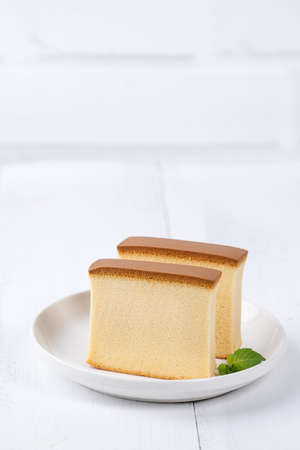 Castella (kasutera)-Beautiful delicious Japanese sliced sponge cake food on white plate over rustic white wooden table, close up, copy space design concept.の写真素材