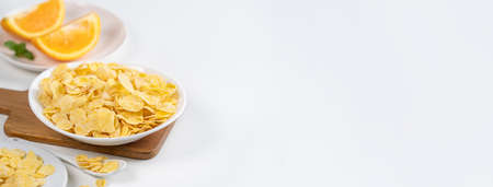 Corn flakes bowl sweeties with milk and orange on white background, close up, fresh and healthy...