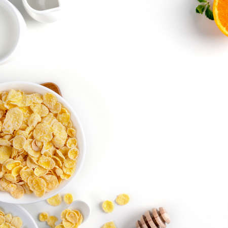 Corn flakes bowl sweeties with milk and orange on white background, top view, flat lay overhead...