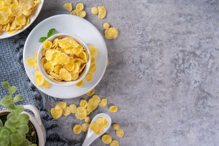 Corn flakes bowl sweets on gray cement background, top view flat lay layout design, fresh and...