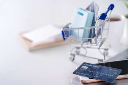Office online paying, stay home shopping, electronic payment with credit card concept, laptop on white table background with shop cart, close up.の写真素材