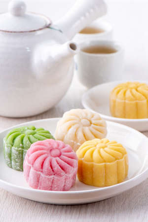 Colorful snow skin moon cake, sweet snowy mooncake, traditional savory dessert for Mid-Autumn Festival on bright wooden background, close up, lifestyle.の写真素材