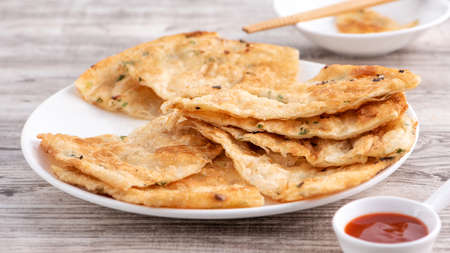 Taiwanese food-delicious flaky scallion pie pancakes on bright wooden table background, traditional...