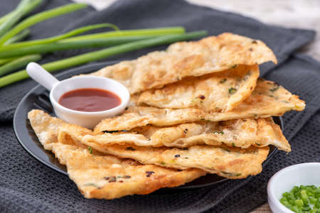 Taiwanese food-delicious flaky scallion pie pancakes on bright wooden table background, traditional...