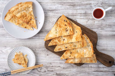 Taiwanese food-delicious flaky scallion pie pancakes on bright wooden table background, traditional...
