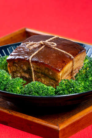 Dong Po Rou (Dongpo pork meat) in a beautiful blue plate with green broccoli vegetable, traditional festive food for Chinese new year cuisine meal, close up.の写真素材
