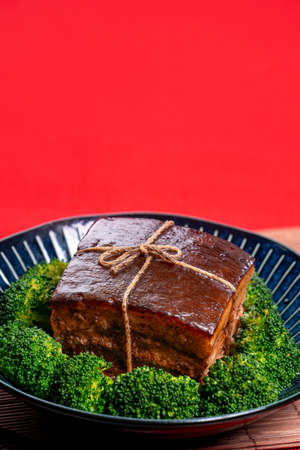 Dong Po Rou (Dongpo pork meat) in a beautiful blue plate with green broccoli vegetable, traditional festive food for Chinese new year cuisine meal, close up.の写真素材