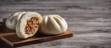 Delicious baozi, Chinese steamed meat bun is ready to eat on serving plate and steamer, close up,...