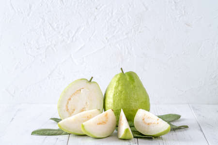 Delicious beautiful Guava set with fresh leaves isolated on bright white wooden table background, close up.の写真素材