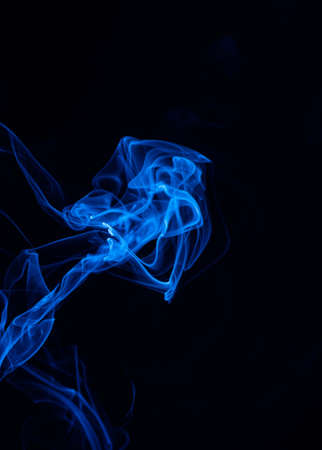 Conceptual image of blue color smoke isolated on dark black background, Halloween concept design element.の写真素材