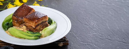 Dong Po Rou (Dongpo pork meat) in a beautiful plate with green vegetable, traditional festive food for Chinese new year cuisine meal, close up.の写真素材