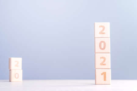 2021 New Year abstract design concept-Number wood block cubes isolated on wooden table and light mist blue background.の写真素材