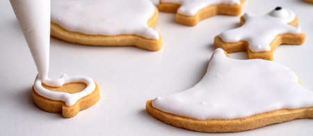Close up of decorating cute Halloween gingerbread cookies with frosting icing cream topping bag.の写真素材