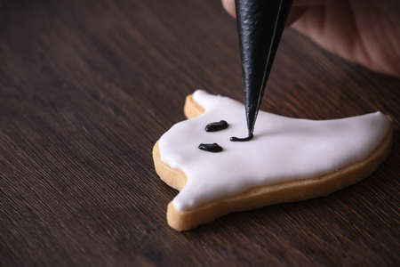 Close up of decorating cute Halloween ghost gingerbread cookies with frosting icing cream topping bag.の写真素材