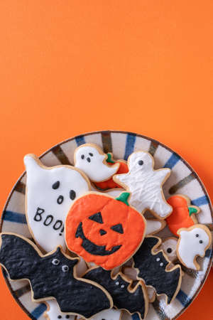 Top view of Halloween festive decorated icing gingerbread sugar cookies on orange background with copy space and flat lay layout.の写真素材