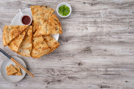 Taiwanese food-delicious flaky scallion pie pancakes on bright wooden table background, traditional snack in Taiwan, top view.の写真素材