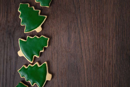Top view of decorated green plain flavor gingerbread Christmas tree cookie on wooden table background with copy space, concept of holiday celebration.の写真素材