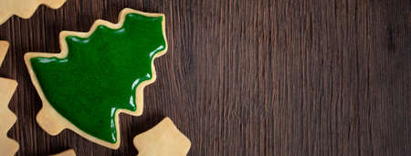 Top view of decorated Christmas tree gingerbread cookie on wooden table background with copy space, concept of holiday celebration.の写真素材