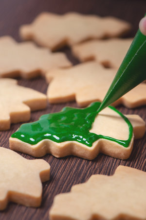 Close up of drawing gingerbread Christmas tree sugar cookie on wooden table background with green icing, concept of holiday celebration.の写真素材