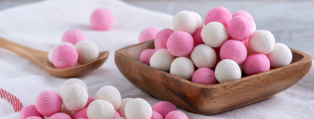 Raw red and white tangyuan glutinous rice dumpling balls on wooden table background for Winter...