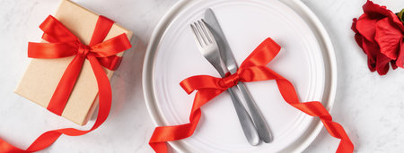 Empty white plate with tableware, ribbon, gift and roses for Valentine's Day special holiday dating meal concept.の写真素材