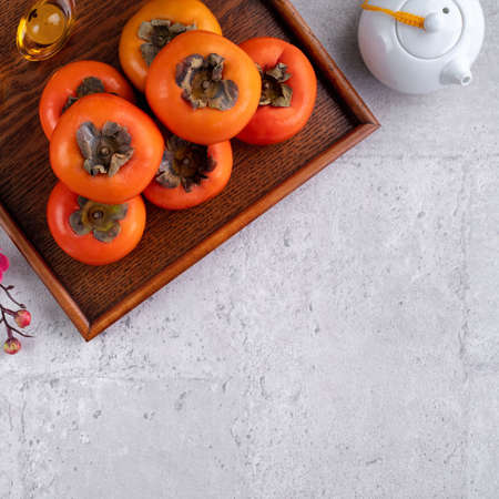 Fresh persimmons on gray table background for Chinese new year fruit designの写真素材