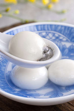 Close up of yuanxiao tangyuan (glutinous rice dumpling balls) in a bowl on gray table with flower, food for Chinese Lantern Yuanxiao Festival.の写真素材