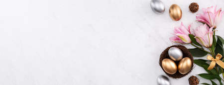 Golden and silver Easter eggs in the nest with pink lily flower on bright marble white table background.の写真素材