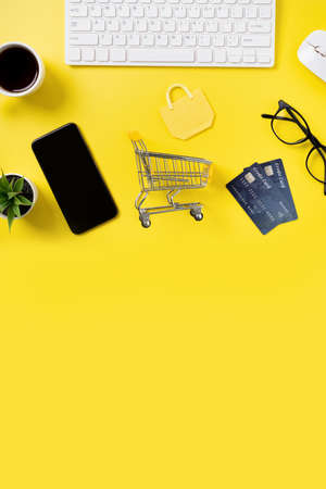 Top view of online shopping concept with credit card, smart phone and computer isolated on office yellow table background.の写真素材