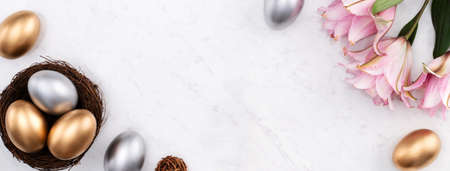 Design concept of Golden and silver Easter eggs in the nest with pink lily flower on bright marble white table background.の写真素材