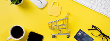 Top view of online shopping concept with credit card, smart phone and computer isolated on office yellow table background.の写真素材